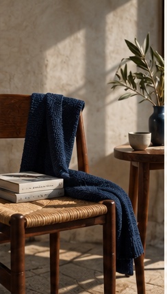 Maglione blu appoggiato su una sedia impagliata accanto a un ramo d'ulivo